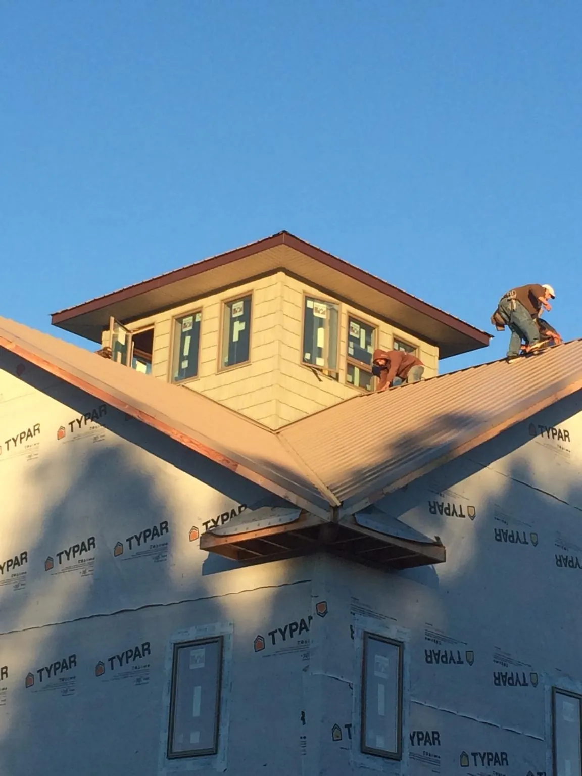 Roofers working around a rooftop cupola on a new metal roof at sunset — Roof Waterproofing in Virginia City by Roofing Brothers
